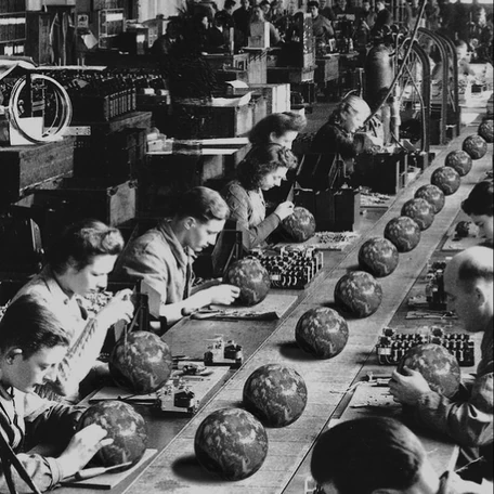 Rows of workers assembling globes along a factory bench